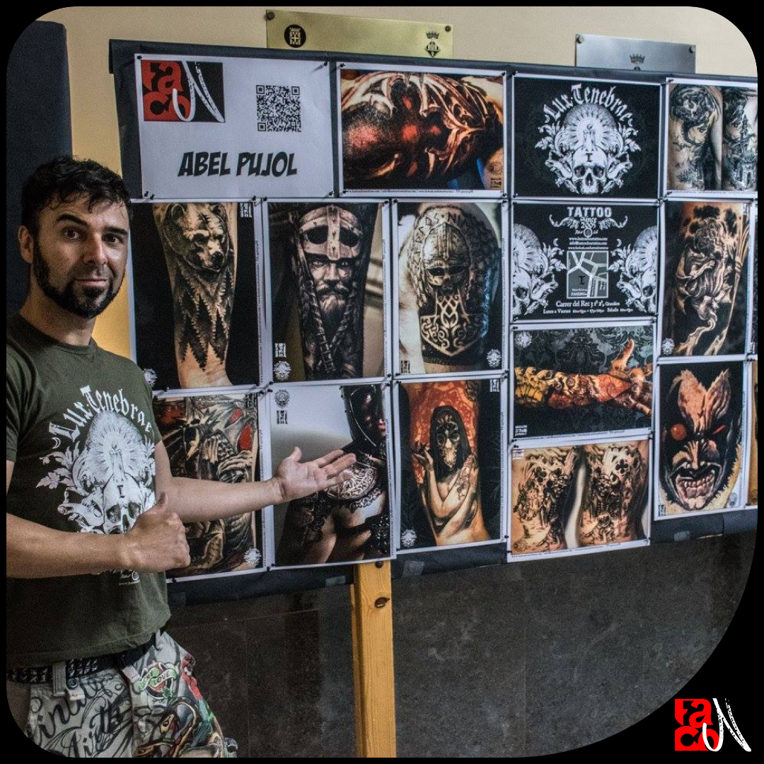 El tatuador Abel Pujol davant d'un mural amb imatges dels seus tattoos